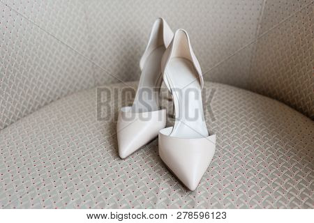 Pair Of White Shoes Commonly Called Dorsay On Beige Chair.