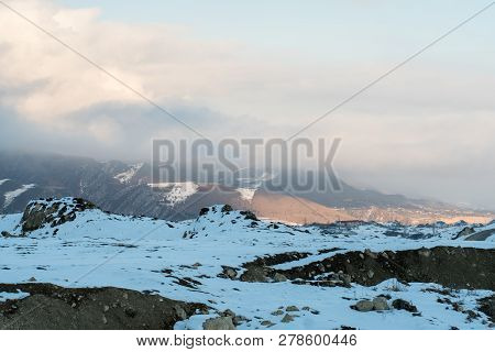 At A Snowy Mountain Peak. Half Of Mountain Range Covered With Snow.