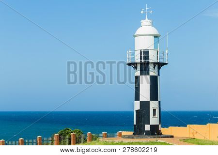 Lighthouse Black And White On Headland Point  Overlooking Windy Blue Ocean For Shipping Marine Night