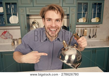 Happy Man In Blue Shirt Point Finger At Kettle. Kitchen Appliance And Furniture. Food Preparation, C