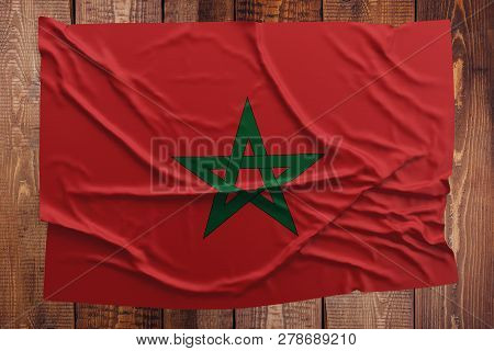 Flag Of Morocco On A Wooden Table Background. Wrinkled Moroccan Flag Top View.