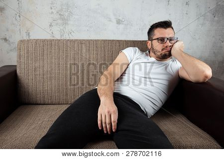 The Guy In The White Shirt Is Lying On The Couch. The Concept Of Laziness, Apathy, Frustration, Proc