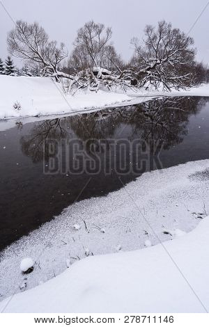 Dull Sunless Winter Landscape. Dark River In Ice And Trees On Snowy Banks Copyspace