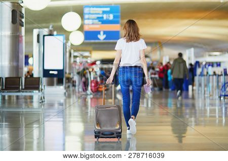 Young Woman In International Airport Walking With Luggage, Ready For Her Flight