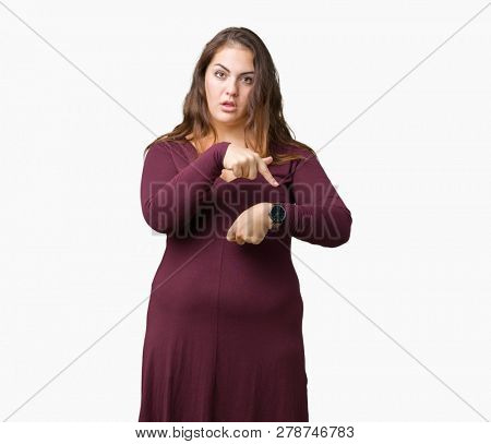 Beautiful and attractive plus size young woman wearing a dress over isolated background In hurry pointing to watch time, impatience, upset and angry for deadline delay
