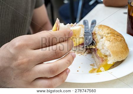 Man Eating Ham And Cheese Sandwich At A Restaurant