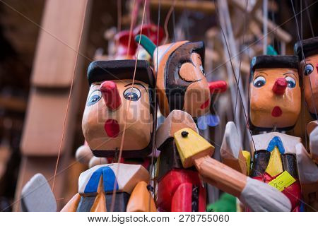 Set Of Wooden Pinocchio Dolls With His Long Nose On A White Background