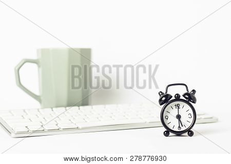 Black Alarm Clock, A Cup Of Coffee Or Tea And A Keyboard On A White Background. Office Concept, Comp