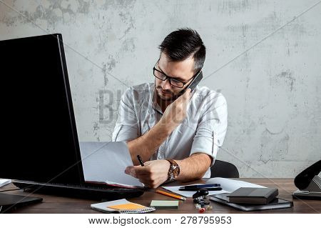 A Man, A Man Sitting At A Table In The Office, Talking On The Phone, Decides An Important Question.