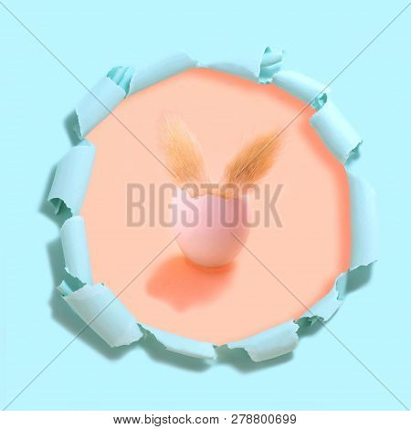 Easter Bunny In Egg. Eggshell With Fluffy Ears Of Easter Bunny. Peach Background Under Tattered Ligh