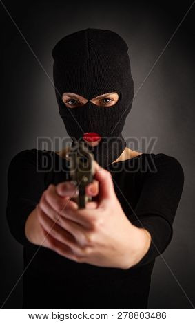 Slim Sexy Girl In Dark Inconspicuous Clothes Hiding Her Face Under A Balaclava Hat With A Gun On A G