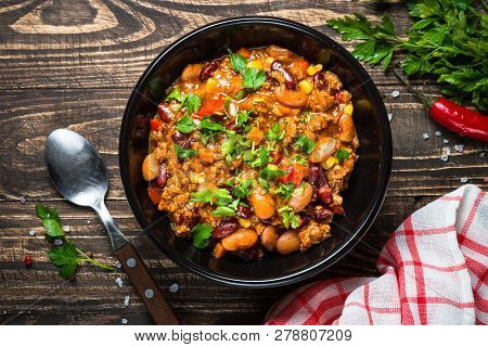 Chili Con Carne From Meat, Beans And Vegetables On Dark Wooden Table. Traditional Mexican Food. Top 