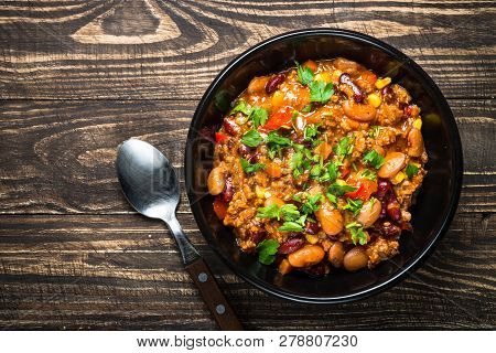 Chili Con Carne From Meat, Beans And Vegetables On Dark Wooden Table. Traditional Mexican Food. Top 