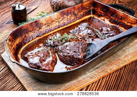 Traditional German braised veal cheeks in brown sauce with mushroom and onions as closeup in a stewpot 