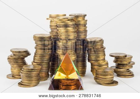 Glass Pyramid In The Foreground, In The Background Large Stacks Of Coins