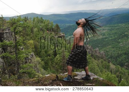 Celt On The Edge Of A Cliff In The Woods Waving His Head With Dreadlocks