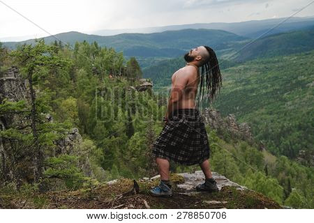 Celt On The Edge Of A Cliff In The Woods Waving His Head With Dreadlocks