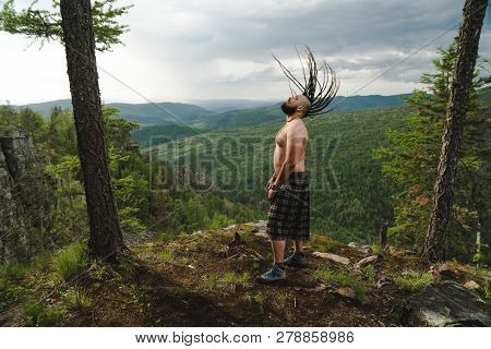 Celt On The Edge Of A Cliff In The Woods Waving His Head With Dreadlocks