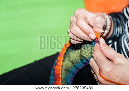 Hand Of Old Woman Holding Knitting Needles And Multi Colored Wool For Woolwork Of Warm Sweater For C
