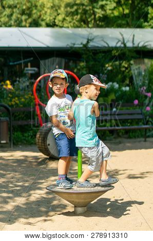 Poznan, Poland - July 29, 2018: Two Boys Playing On A Spinning Equipment At A Playground On A Sunny 