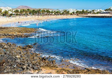 Golden Sand And Volcanic Rocks At Las Cucharas Beach, Lanzarote, Canary Islands. View Of The Sea, Co