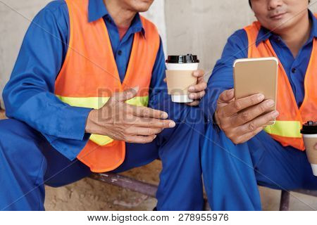 Constructon Workers Discussing News On Smartphone During Coffee Break At Work