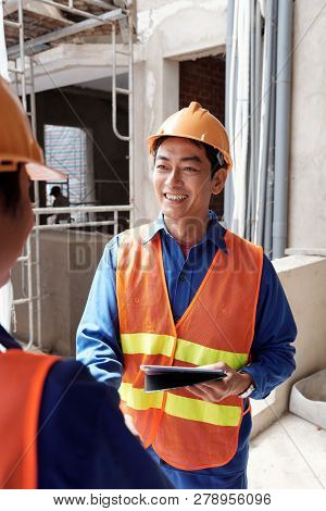 Cheerful Mature Vietnamse Contractor Meeting New Worker At Construction Site