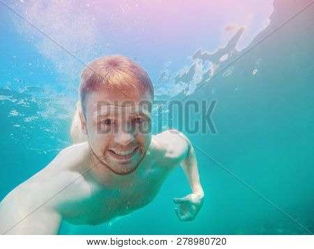 Man Under Water In Turquoise Sea. Concept Of Pain From Bite Jellyfish.
