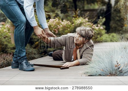 Man Helping Female Senior To Get Up From The Ground