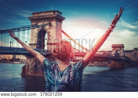 Beautiful Grateful And Thankful Young Urban Woman Arms Raised In Sunrise At City. Travel Destination