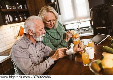 Seniors Couple At Home Measuring Blood Pressure And Make Healthy Juices. Home Monitoring
