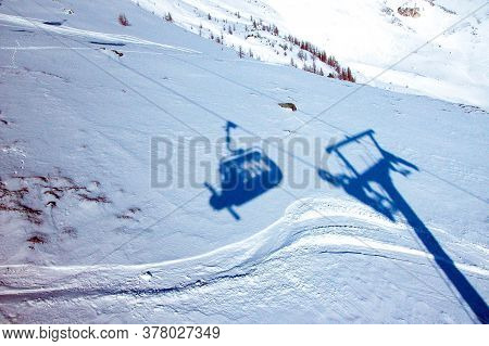 Shadow Of A Chairlift In Alpine Ski Area, Mountain Slope Covered In Snow