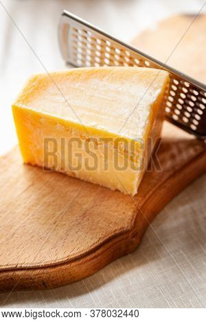 Cheese And Grater. Close-up Of A Piece Of Parmesan On A Wooden Board. Fine Grater For Grating Cheese