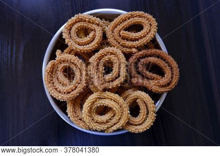 A Top Shot Of Cultural Homemade Murukoo Snacks In Plate On Dark Wooden Table