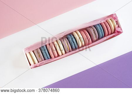 Multicolored Macarons In A White Box On A White, Pink, Violet Background