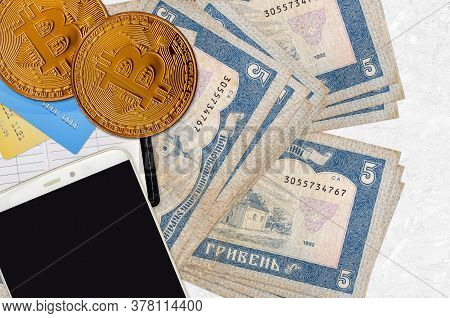 5 Ukrainian Hryvnias Bills And Golden Bitcoins With Smartphone And Credit Cards. Cryptocurrency Inve