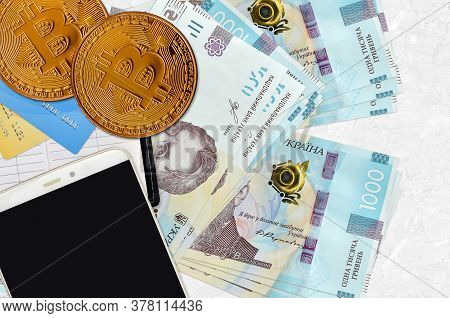 1000 Ukrainian Hryvnias Bills And Golden Bitcoins With Smartphone And Credit Cards. Cryptocurrency I