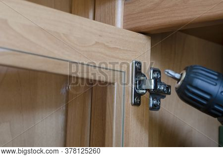 Cabinet Door Hinge Adjustment. Assembly And Repair Of Furniture Using An Electric Screwdriver. Comme