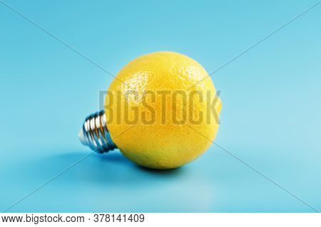 Lemon Light Bulb On A Blue Background. The Fruit Of A Lemon With Base From The Bulb E27.