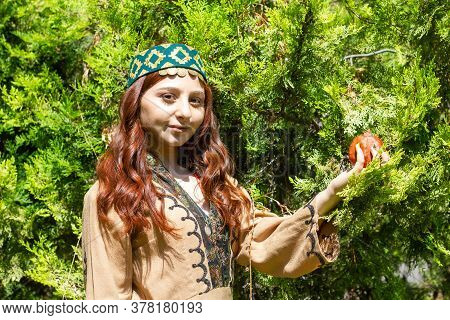 Armenian Young Woman In Traditional Clothes In The Forest With Pomegranate