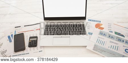 Laptop On Table With Finance Statements, Calculator On White Background