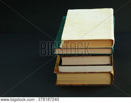 5 Old Books, One On Top Of The Other On A Black Background, The Top Book Is A Little Dirty