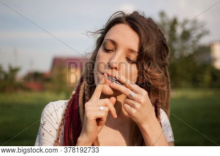 Close-up Outdoors Portrait Of Young Female Shaman With Long Dreadlocks Playing On Traditional Hutsul