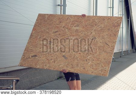 A Man Carries A Wooden Plate For Construction.