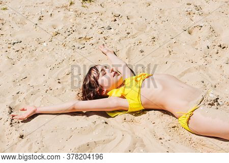 Young Woman Lies In Summer On The Beach. The Girl Lies On The Sand On The Beach. Teenager At Sea. Va