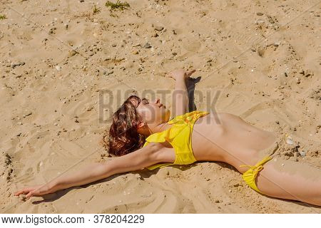 Young Woman Lies In Summer On The Beach. The Girl Lies On The Sand On The Beach. Teenager At Sea. Va