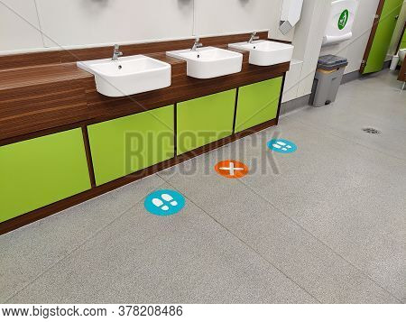 Signs On A Floor Indicating Socal Distancing In A Mens Bathroom