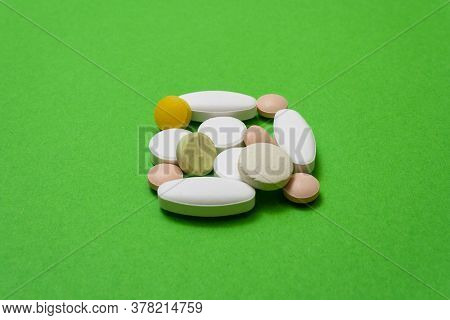 Bunch Colorful Round Pills And Capsules On A Green Background Close Up, Macroshot Tablets, Isolated.