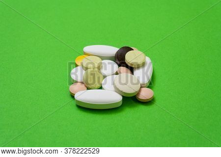 Bunch Colorful Round Pills And Capsules On A Green Background Close Up, Macroshot Tablets, Isolated.