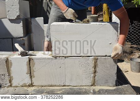 A Bricklayer Is Laying A Wall From Large Gas Autoclaved Aerated Concrete Blocks Using A Trowel And A